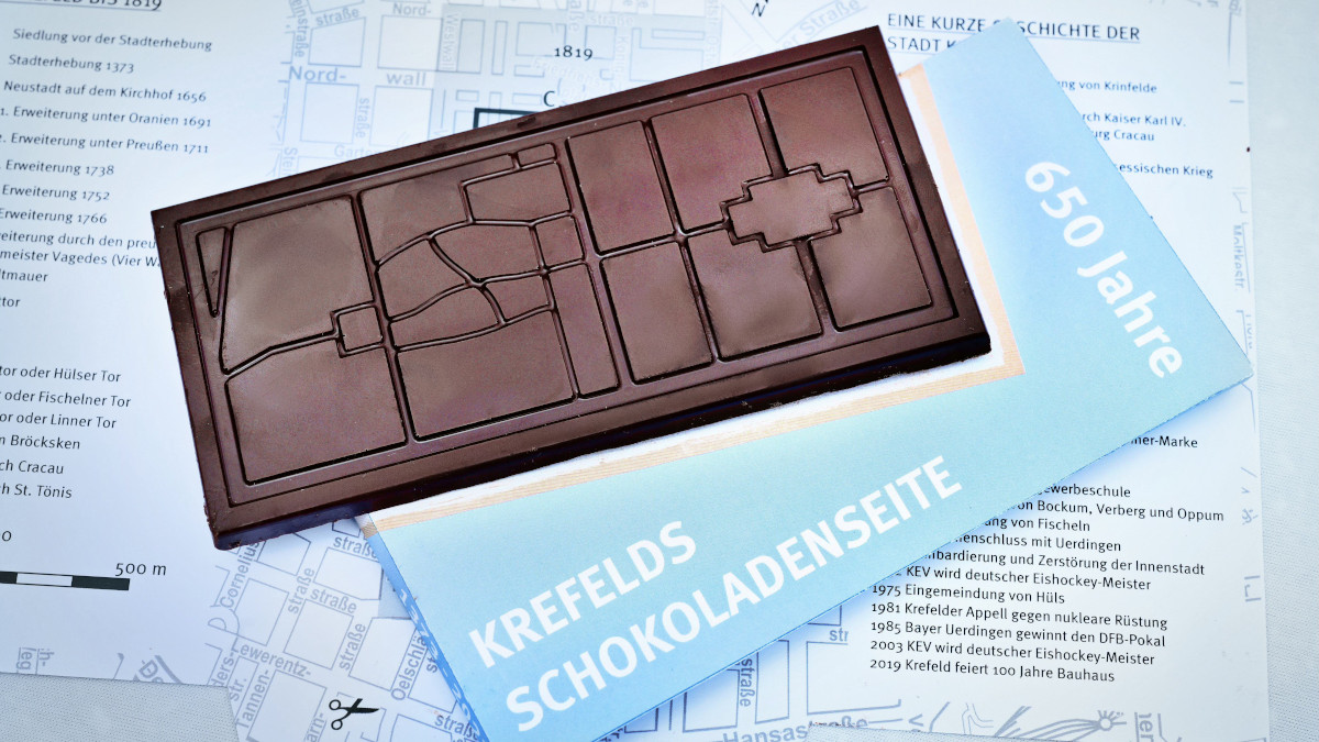 Die Jubiläumsschokolade bildet den Bereich zwischen den vier Wällen ab. Ummantelt wird die Schokolade von einem Stadtplan mit Geschichten aus der Stadt. Bild: Stadt Krefeld, Presse und Kommunikation